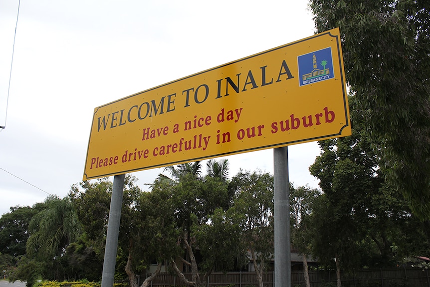 A yellow sign reading "Welcome to Inala, Have a nice day, Please drive carefully in our suburb".