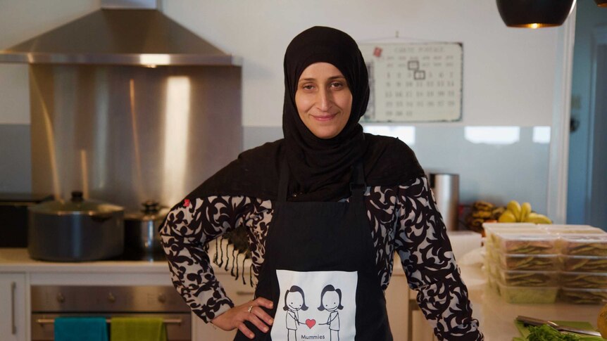 A woman in a headscarf smiles in a kitchen
