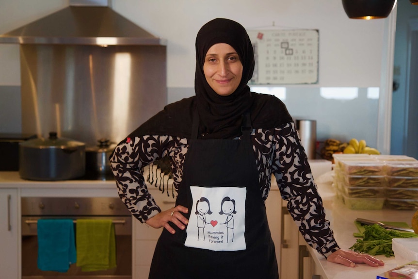 A woman in a headscarf smiles in a kitchen
