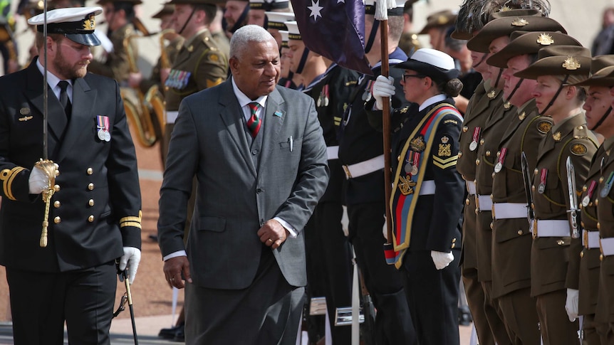 Mr Bainimarama walks past saluting Australian soldiers.
