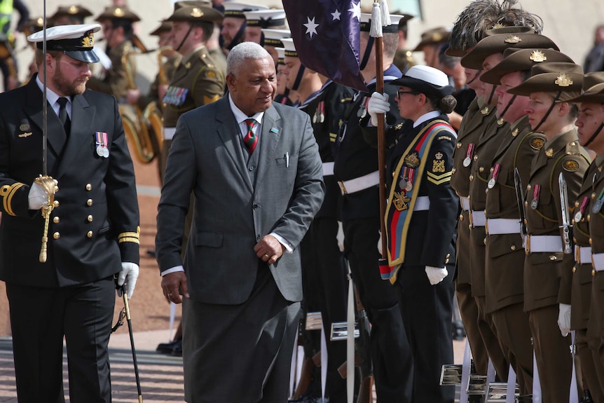 Mr Bainimarama walks past saluting Australian soldiers.