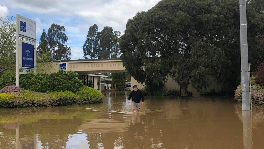 A man walks through knee-deep floodwaters outside a hotel in Seymour