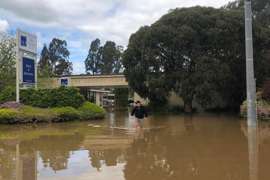 A man walks through knee deep floodwaters outside a hotel in Seymour