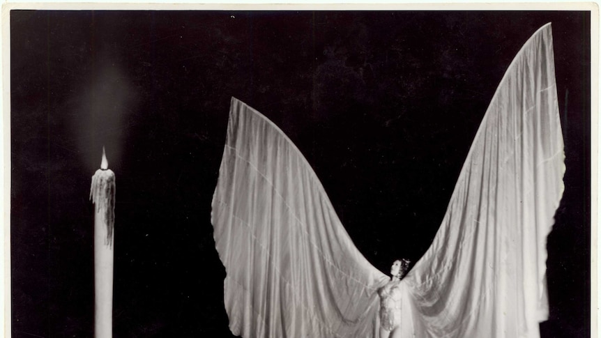 Magic performer Myrtle Roberts on stage wearing huge silk wings during a performance in 1946