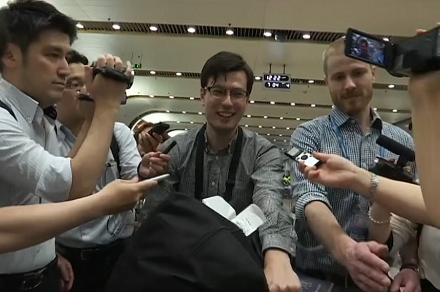 Australian Alek Sigley smiles as he is surrounded by media in Beijing after being released from detention in North Korea