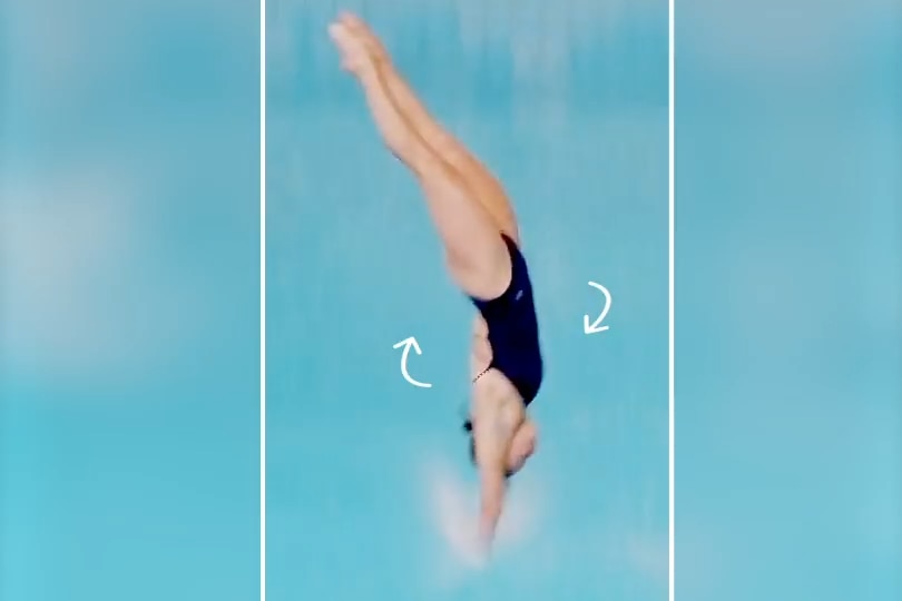 Arms stretched, Nikita hits the water. From the side view, her furthest leg is visible because her body is slightly rotated.