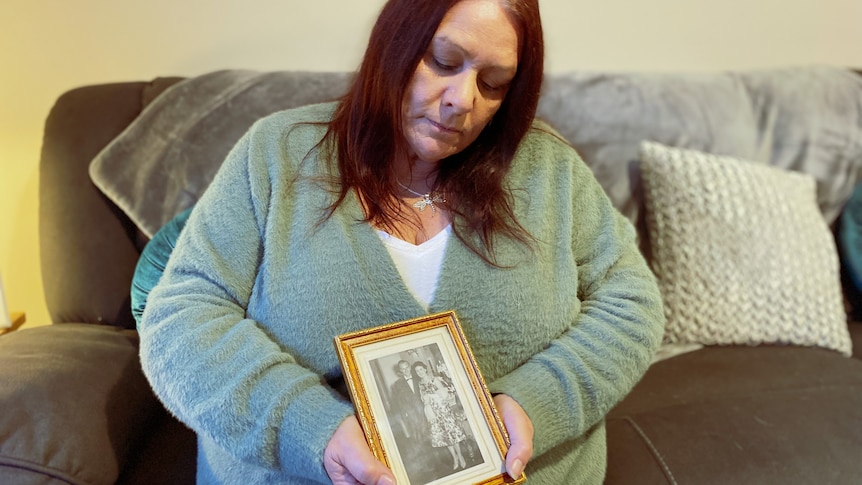 A woman holds a framed black and white photo of a man and a woman.