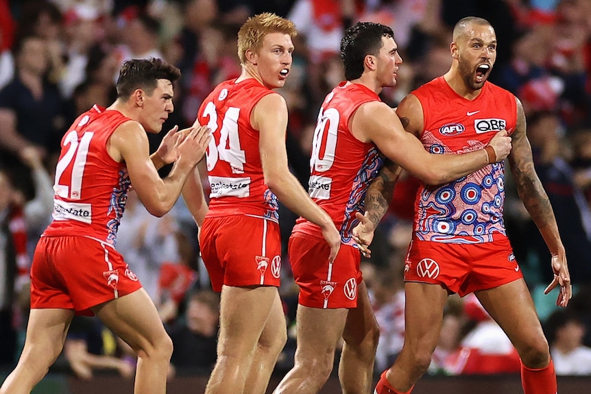 Lance Franklin is surrounded by Swans teammates as he yells