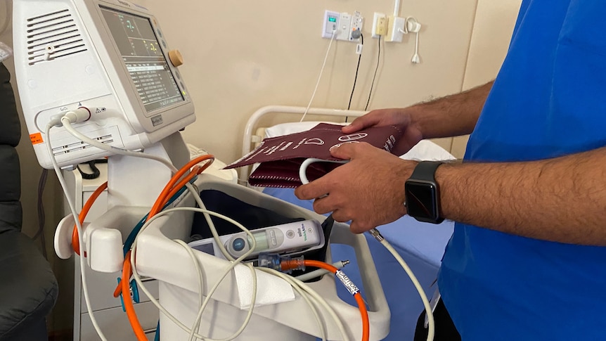 A man with blue scrubs holding a blood pressure band