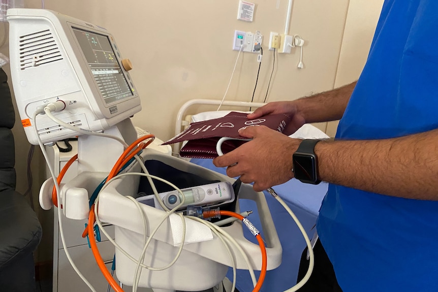 A man with blue scrubs holding a blood pressure band