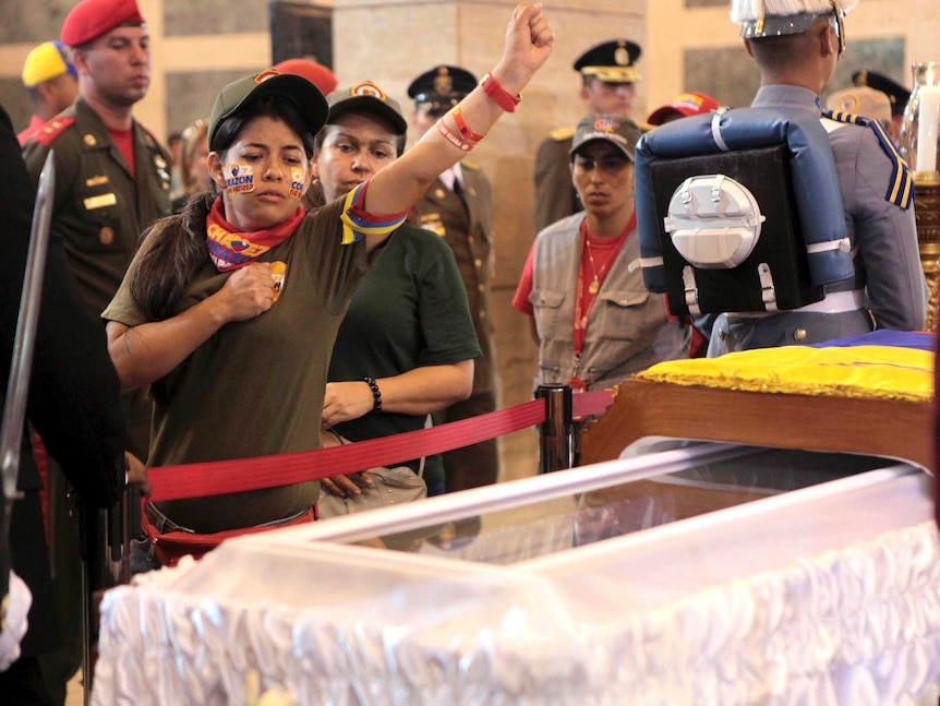 Supporter of Hugo Chavez salutes his coffin.