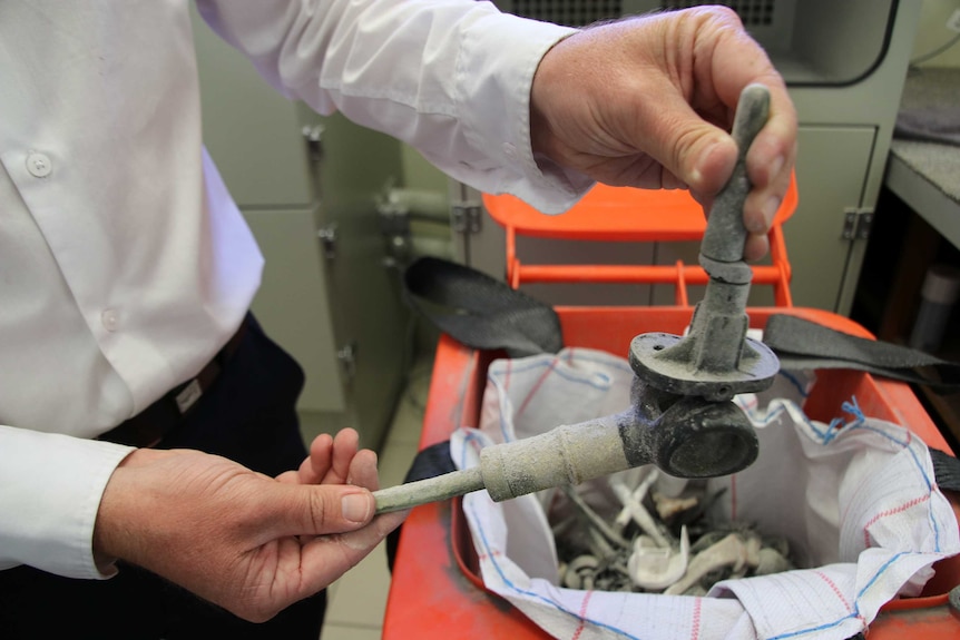 A man's hands holding some of the metal parts to be sent for recycling.