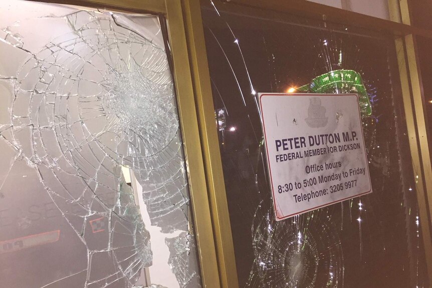A close-up of a smashed window, with federal MP Peter Dutton's office contact details on it.