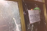 A close up of a smashed window, with Peter Dutton's office contact details on it