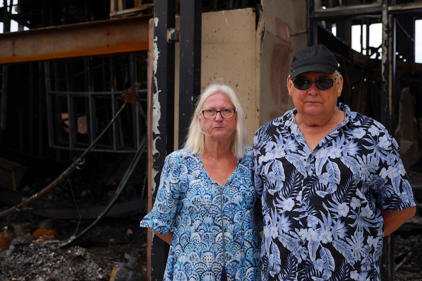 two people standing in front of burnt out house