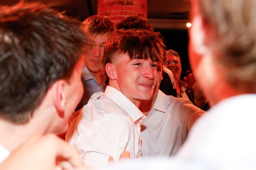 Phoenix Gothard smiles while surrounded by friends at the AFL draft.