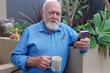 A man with a coffee mug, with a jailed prisoner on it.