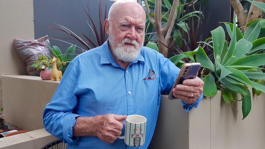 A man with a coffee mug, with a jailed prisoner on it.