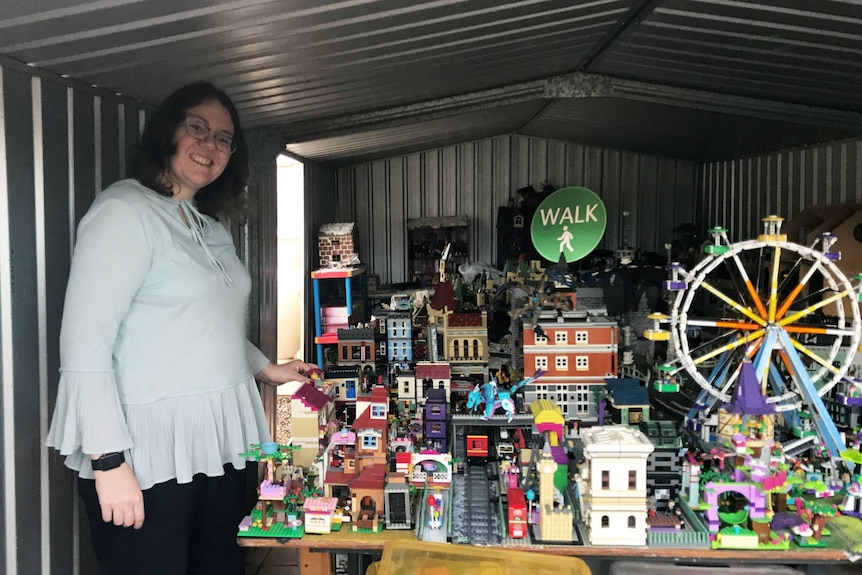 Rebecca Sharrock stands inside a shed full of Lego buildings stretched out across a table.