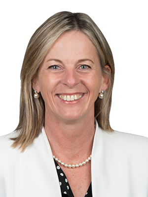 A woman with shoulder-length blond hair, wearing a white jacket, smiles.