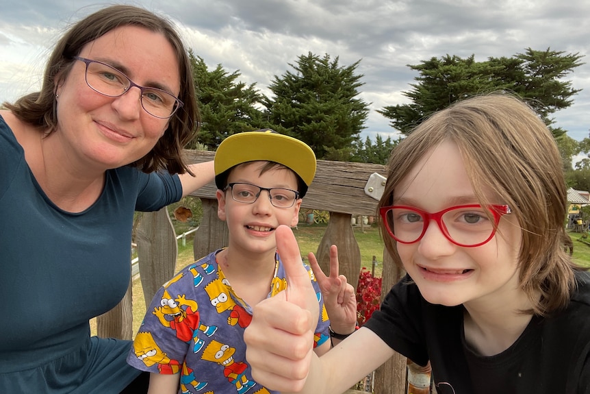 A young white woman with her two young kids. Both are smiling