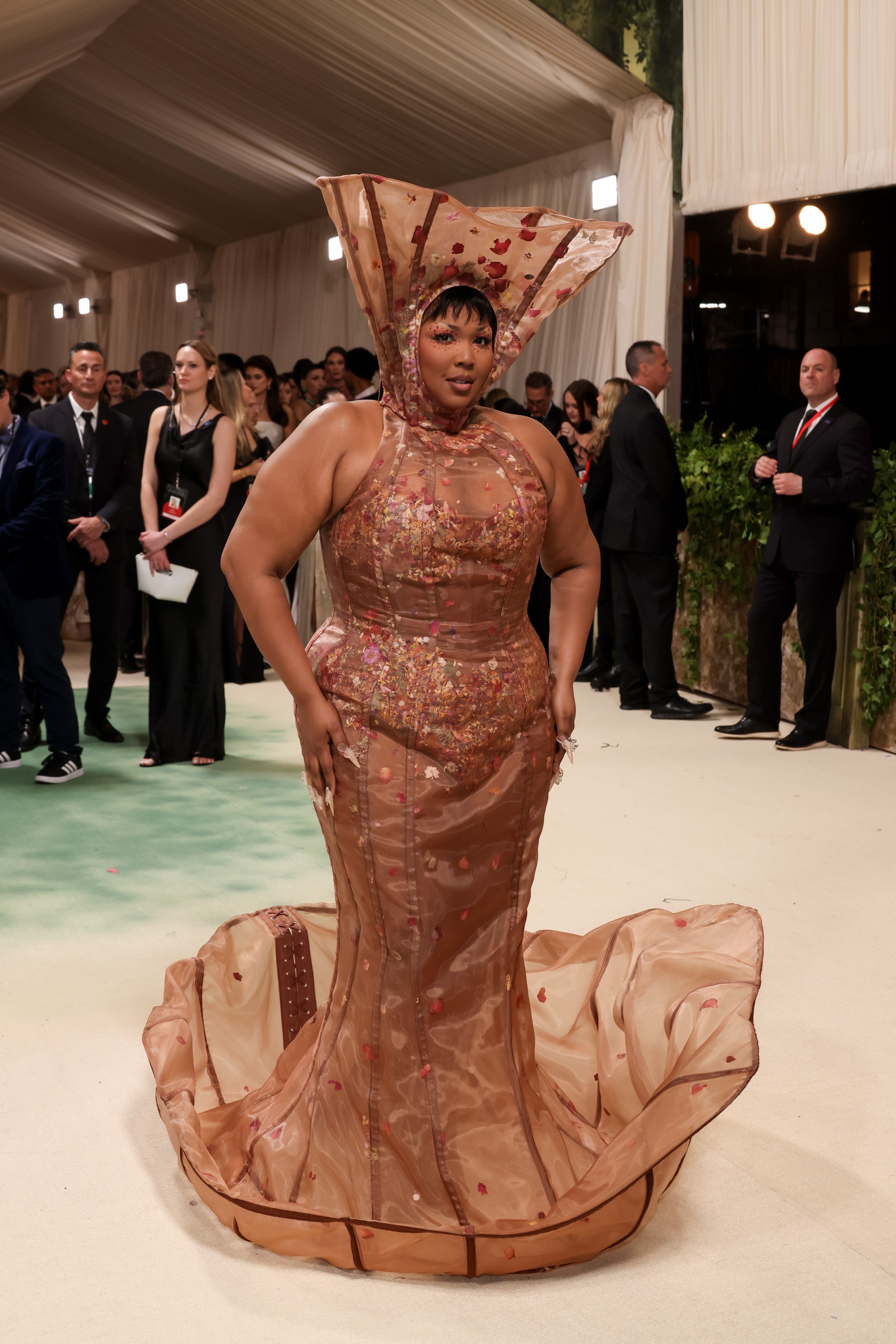 Lizzo wears a sheer dress with a headpiece at the 2024 Met Gala.