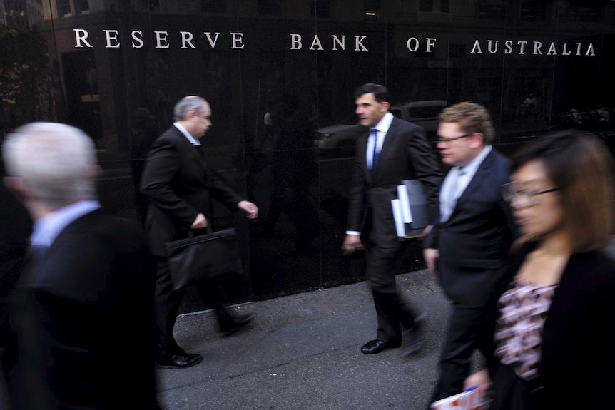 Business people walk outside the Reserve Bank of Australia.