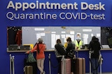 People wait in front of a desk at Schipol airport in Amsterdam marked "Appointment Desk" for COVID testing and quarantine.  