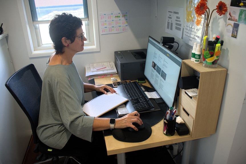 A woman sits at a computer