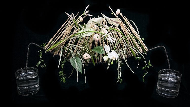 A wire archway decorated with dried bamboo and spring blooms.