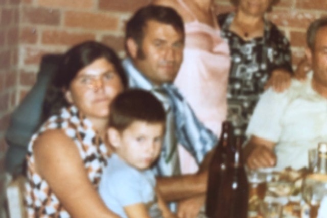 A man sits next to a woman and child.