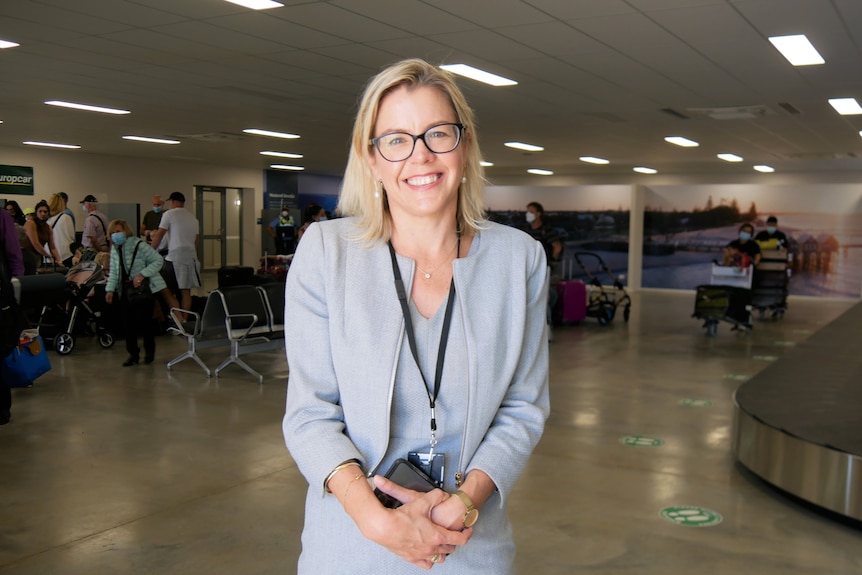 Woman smiles at camera inside airport terminal.