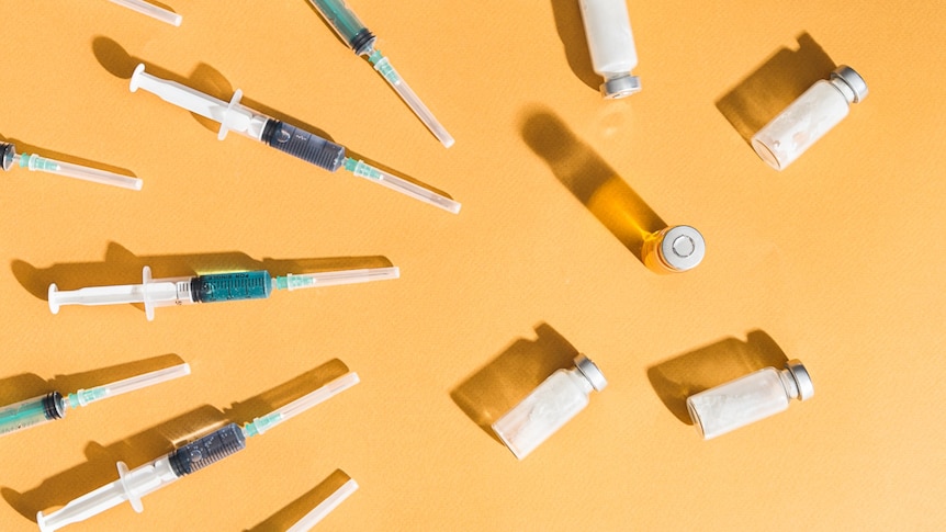 Vaccination syringes and glass bottles on a yellow background