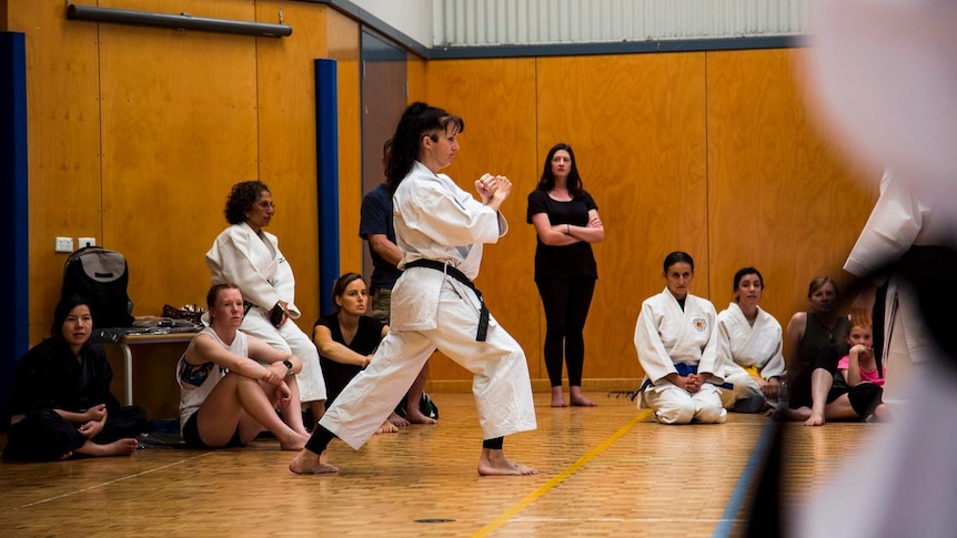 Two women in karate outfits in a gym
