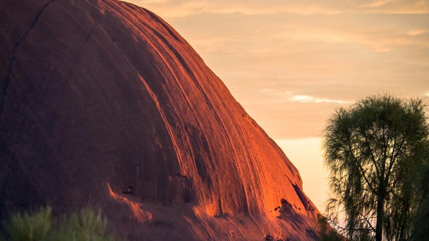 Sunrise creates soft light on the face of Uluru.