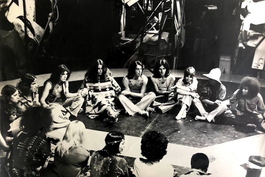 A 1960s black and white photo of a group of young people sitting in a circle