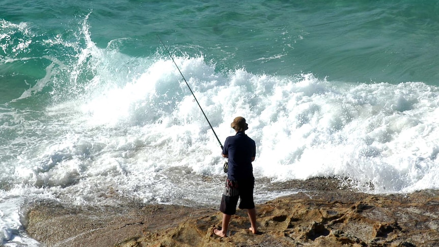 A man fishes off rocks