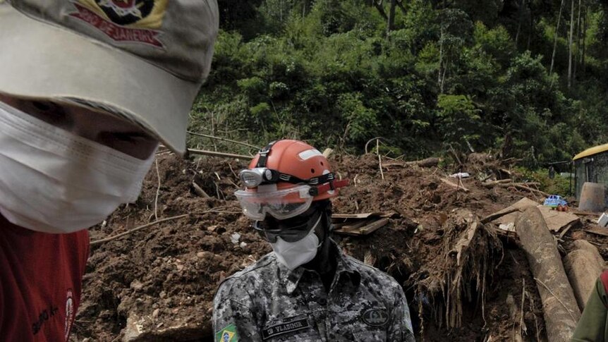 Volunteers and a Brazilian National Force rescue worker carry the body of a man