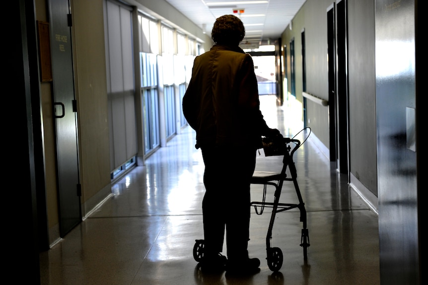 a woman with a walker to assist mobility inside an aged care centre