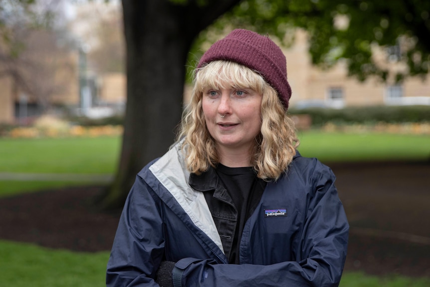 A woman with blonde hair and wearing a beanie speaks.