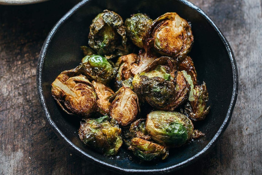 Crispy fried brussels sprouts sit in a bowl with chicken salt, for a story on cooking brussels sprouts.