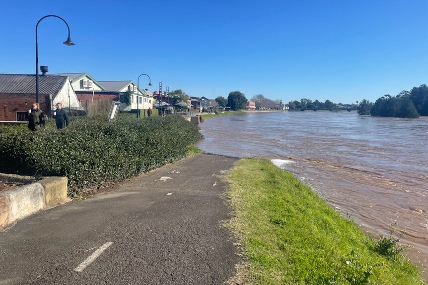 Riverside footpath sumberged by sowllen river. Row of houses to the left, not submerged