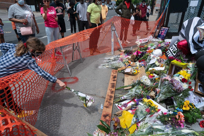 People leave flowers at a makeshift memorial on the side of a road