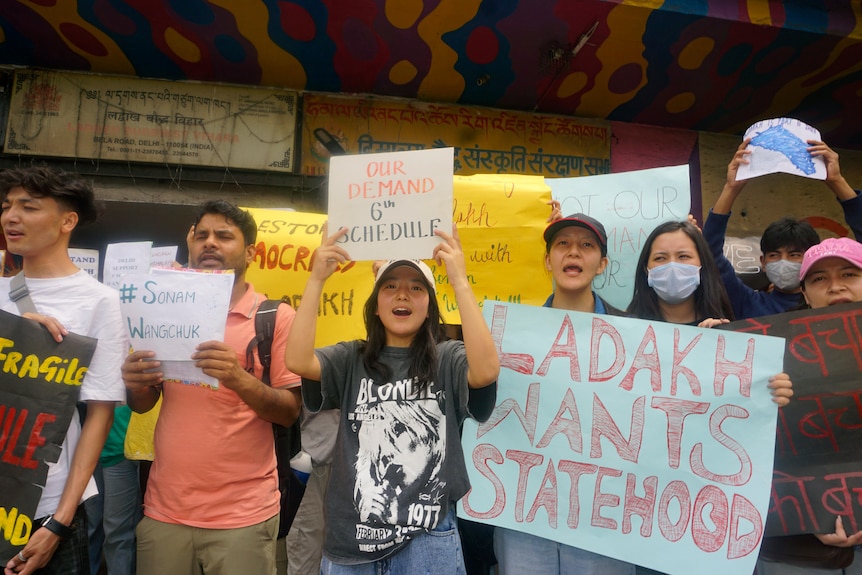 Protesters hold signs demanding statehood from the Indian government
