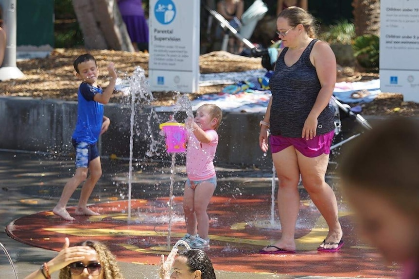 Toddler plays with bucket of water at a pool.