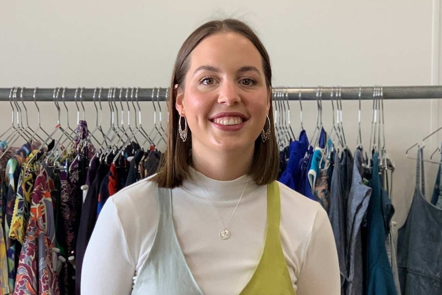 Woman standing in front of a rack of vintage clothing.