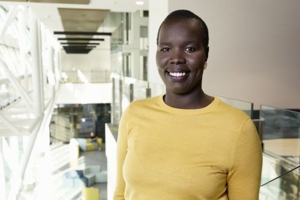 Young African woman with short hair smiling and wearing bright yellow shirt in office environment