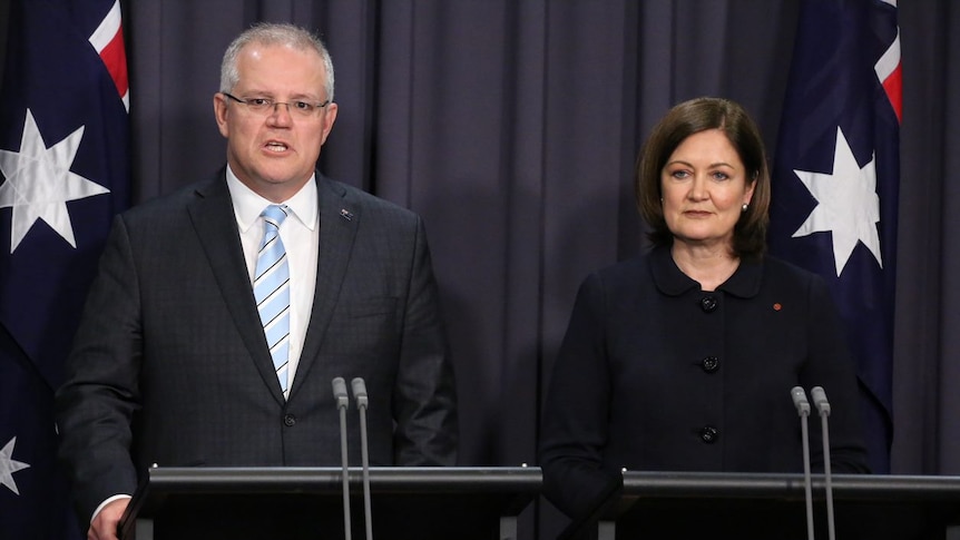 Scott Morrison and Sarah Henderson stand at podiums surrounded by Australian flags