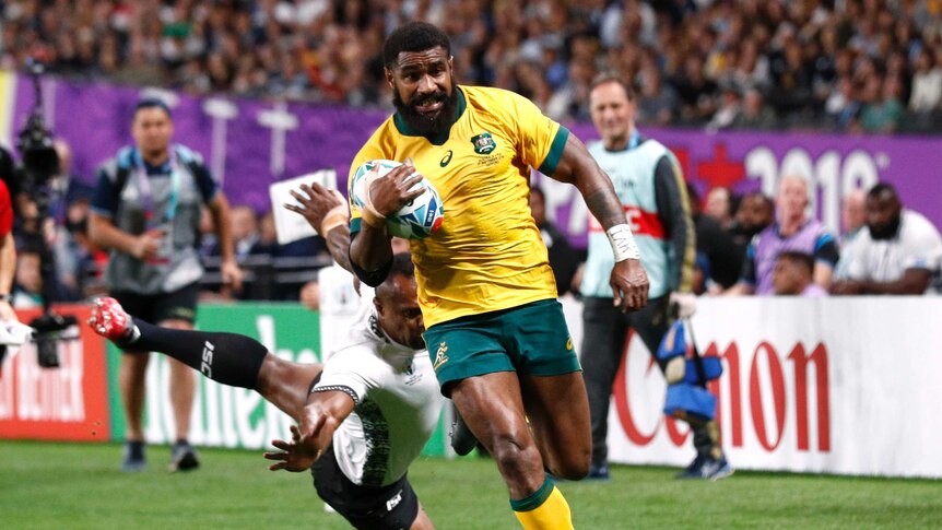 Marika Koroibete runs with the ball under his right arm runs down the touchline with a Fiji player diving behind him