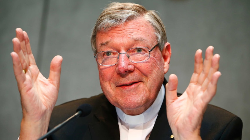 George Pell holds his hands up as he speaks.